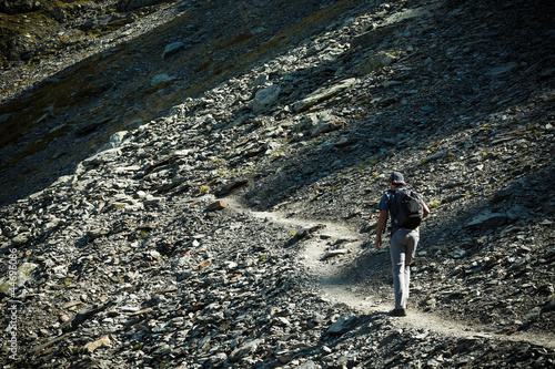 Man walking on mountain trail, hiking to the top