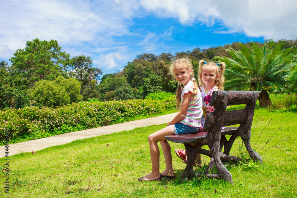 two happy sisters sitting on the bench two happy sisters sitting on the bench