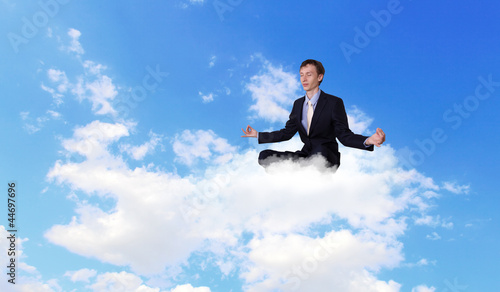 Businessman meditating sitting on the cloud