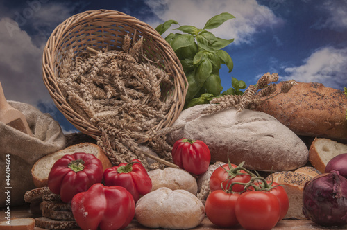 Loaves of bread, rolls and vegetalbes on sky background photo