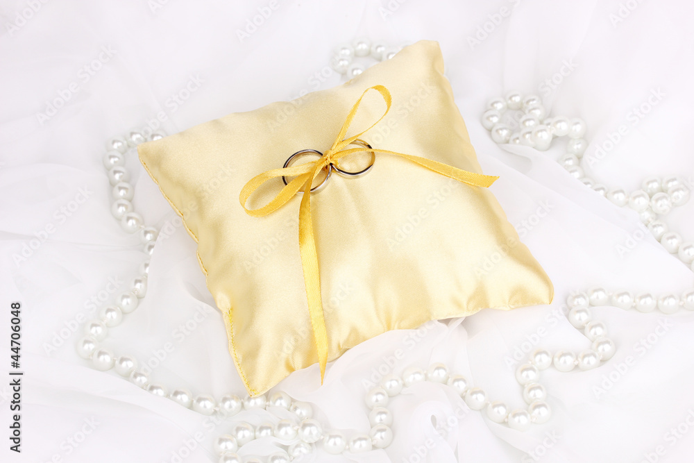 Wedding rings on satin pillow on white cloth background Wedding rings on satin pillow on white cloth background