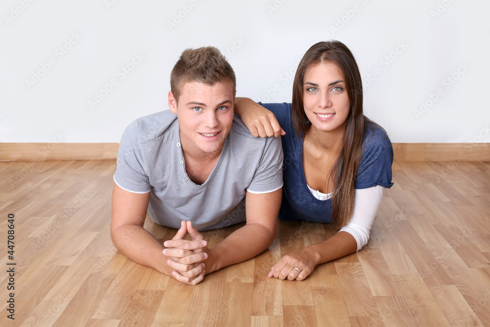 Cute young couple laying on wooden floor Cute young couple laying on wooden floor