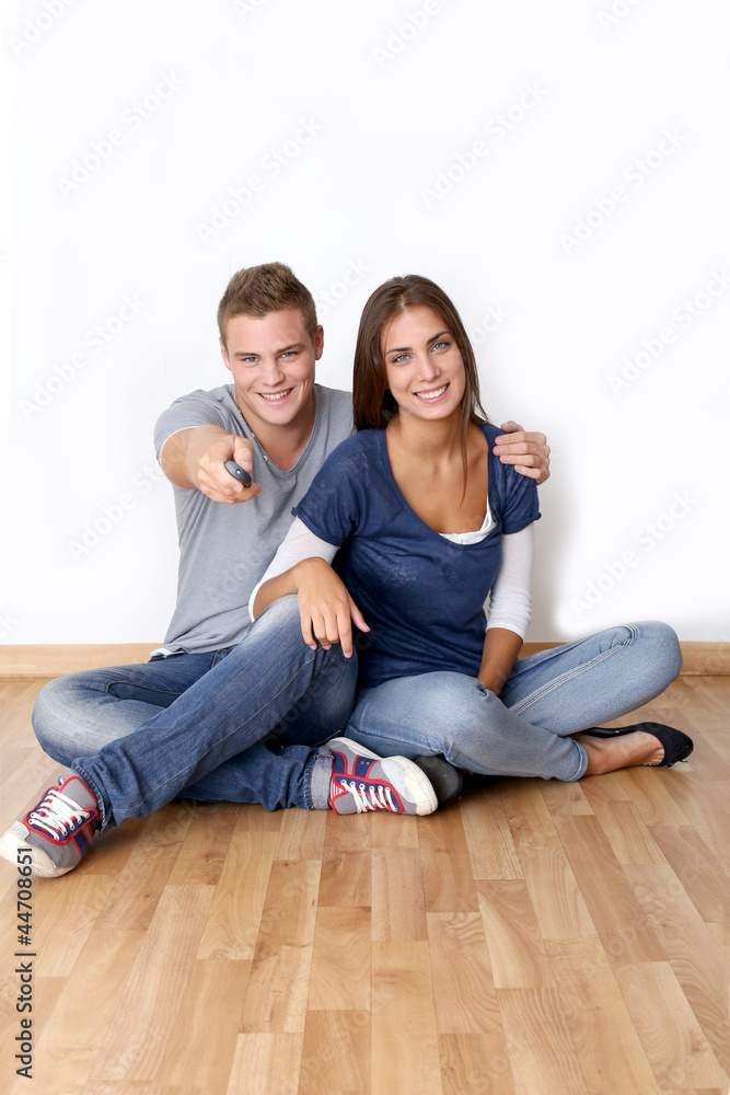 Cheerful young couple using tv remote control Cheerful young couple using tv remote control