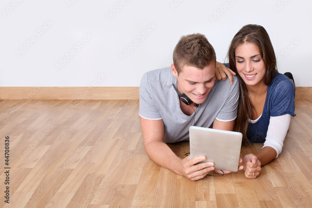 Young people laying on wooden floor with digital tablet