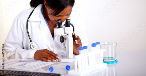 Charming medical doctor female using a microscope