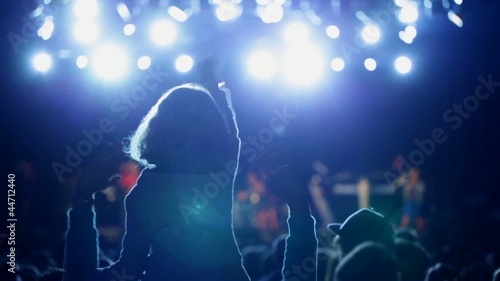 Little girl sitting on her fathers shoulders waving along with music at pop concert