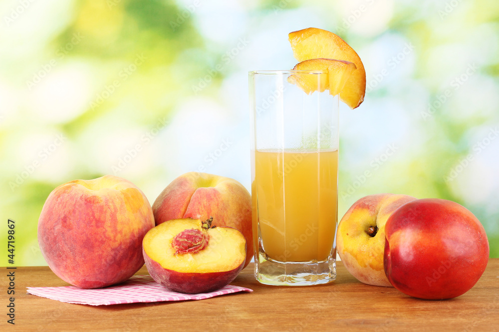 Ripe peaches and juice on wooden table on natural background