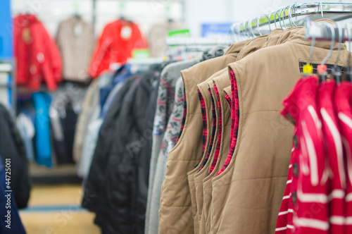 Variety of jackets, vests and sweaters on stands in supermarket