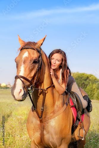 Young girl and horse on a summer meadow on a sunset