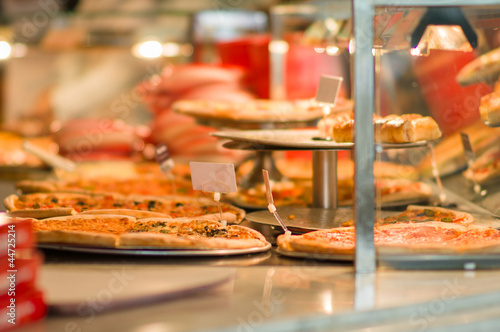 Pizzas under shopping window in fast food restaurant in mall