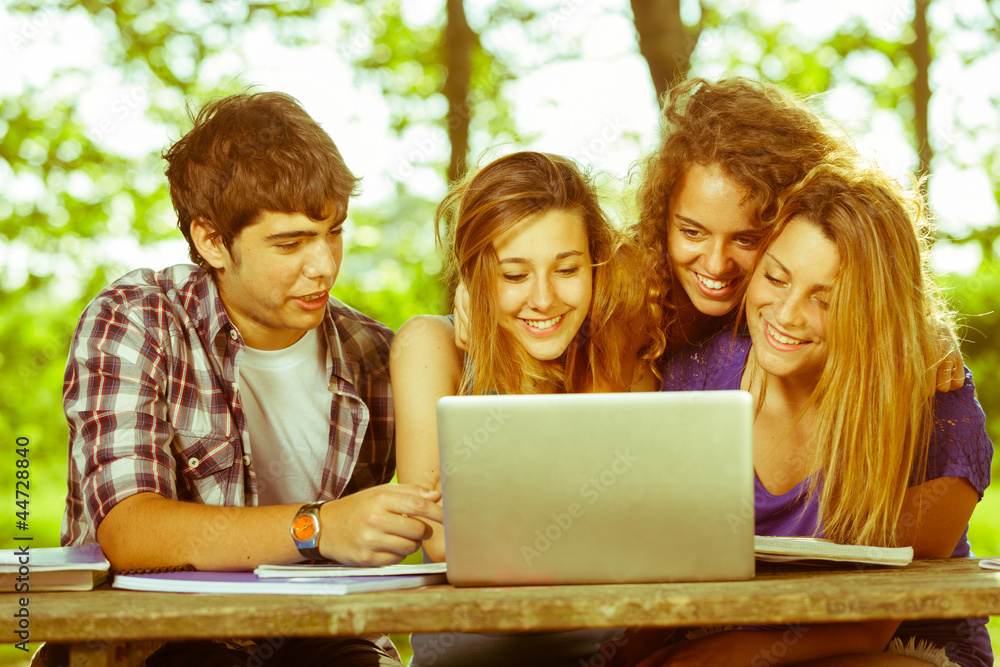 Group of Teenage Students at Park with Computer and Books Group of Teenage Students at Park with Computer and Books