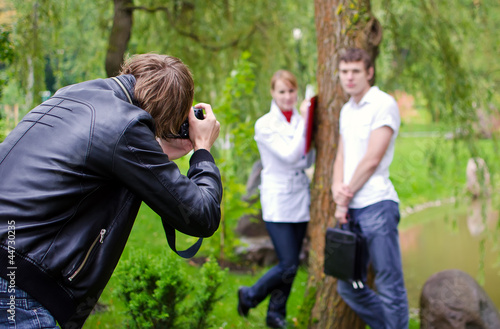 Photographer takes picture of young couple outdoors © M-Production