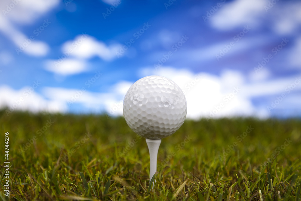 Golf ball on green grass over a blue sky Golf ball on green grass over a blue sky