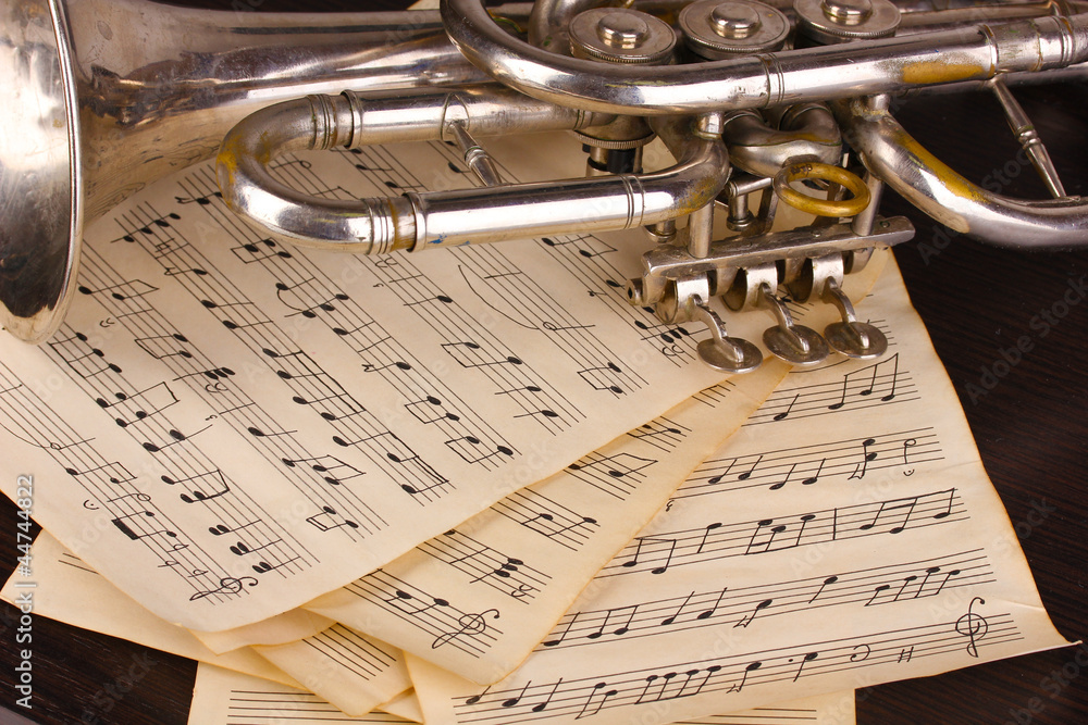 Obraz premium Musical notes and trumpet on wooden table