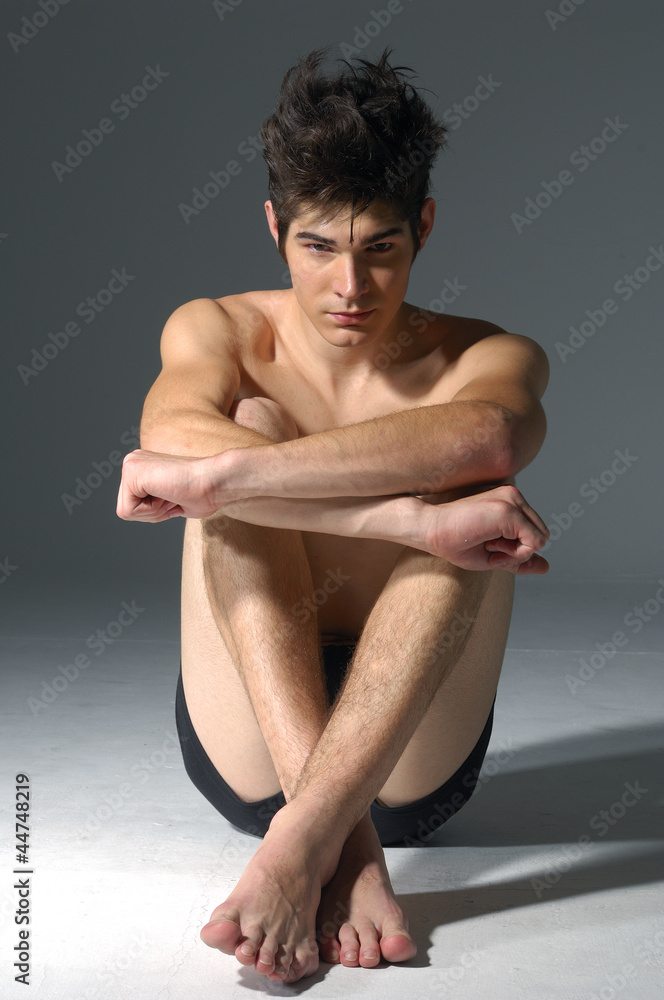 young muscular man, sitting, studio shot