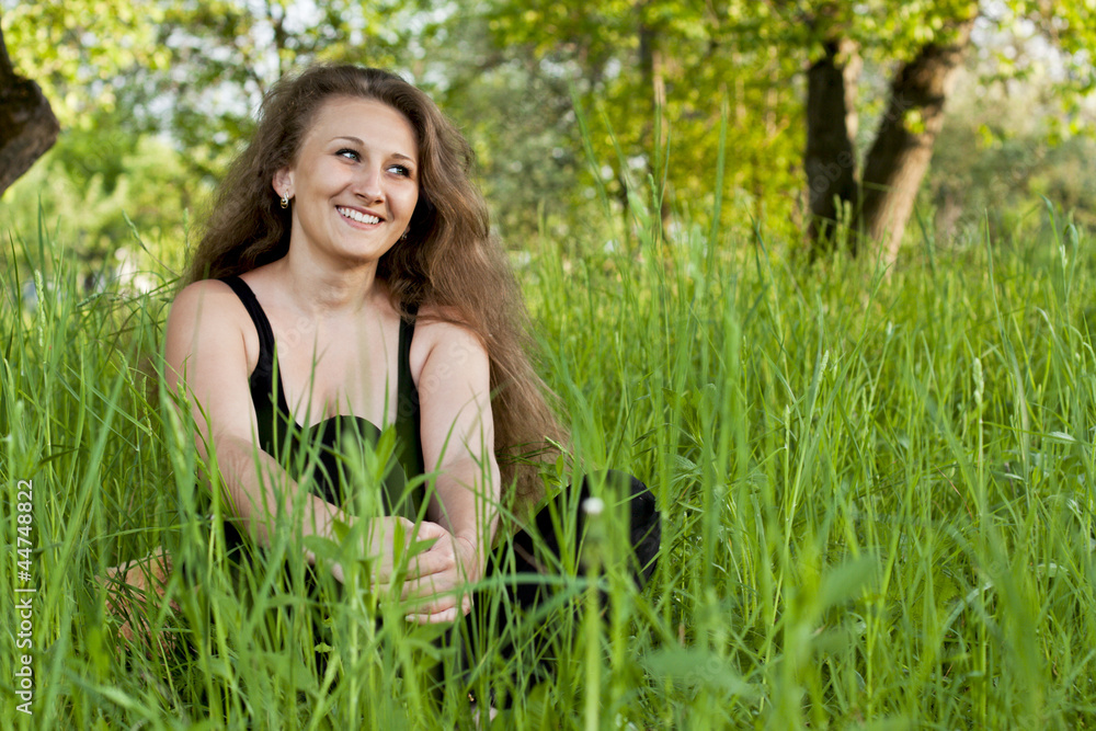 beautiful girl sitting in the green grass