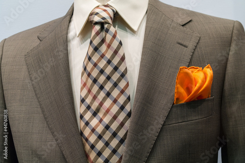 Light grey checkered jacket with brown checkered tie and orange