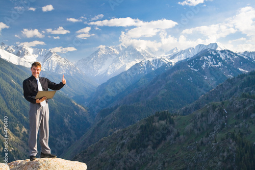 Young businessman with a broad smile on the mountain top