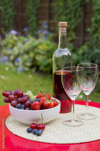 Rose wine with summer fruits on garden table