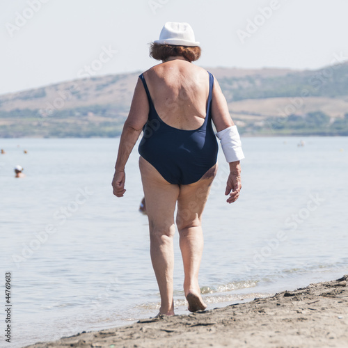 elderly and fat old ladie walk on the beach photo