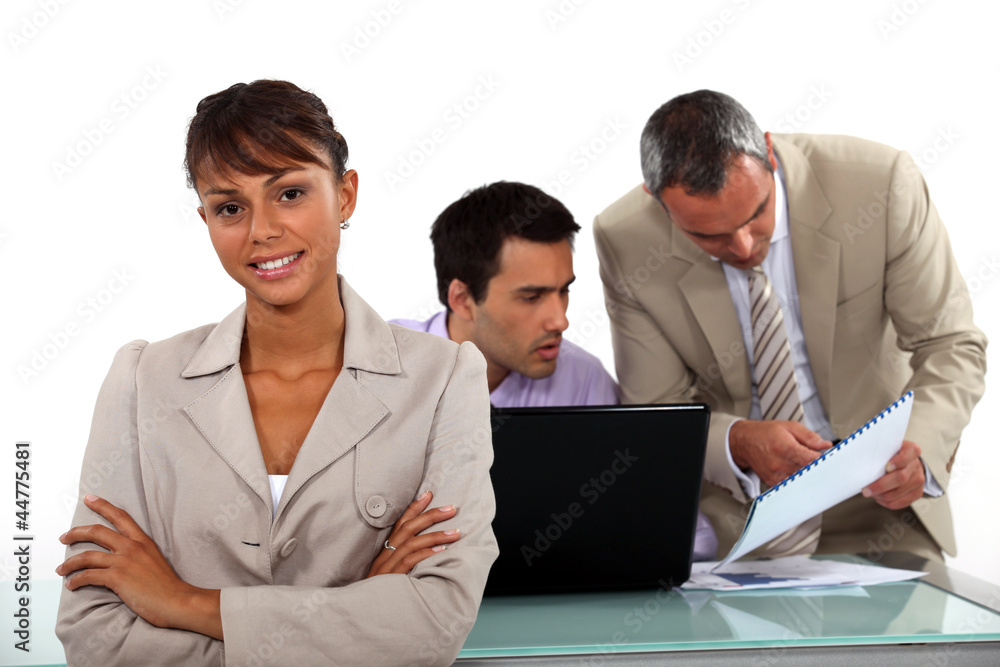 Smiling businesswoman standing in front of male colleagues Smiling businesswoman standing in front of male colleagues