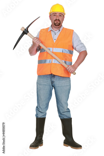 bricklayer holds pickaxe against studio background © auremar