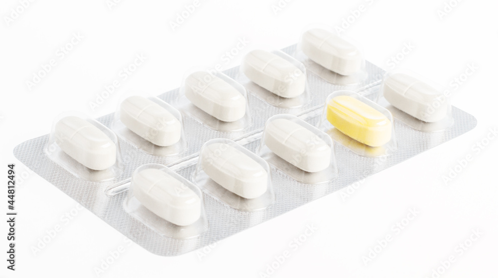 Unique pill shining between white tablets. Uniqueness and indivi Unique pill shining between white tablets. Uniqueness and indivi