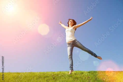 pretty young woman jumping on green grass