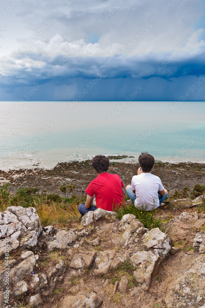 Kids Looking at a Storm over the Sea