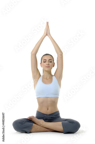 Young woman doing yoga moves or meditating on white