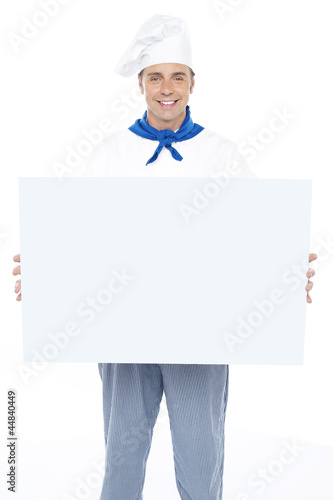 Handsome male chef holding ad board