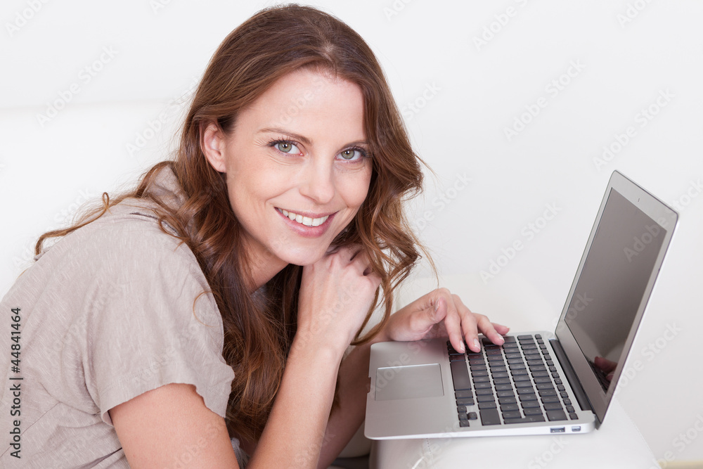 Woman relaxing on sofa using laptop Woman relaxing on sofa using laptop