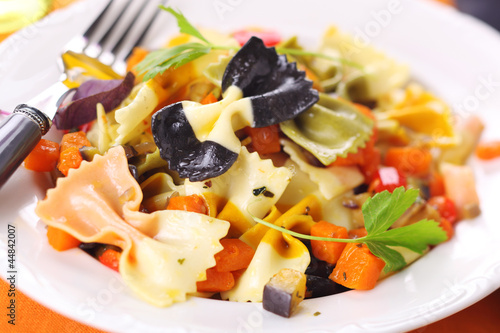 Pasta farfalle with vegetables on white plate.