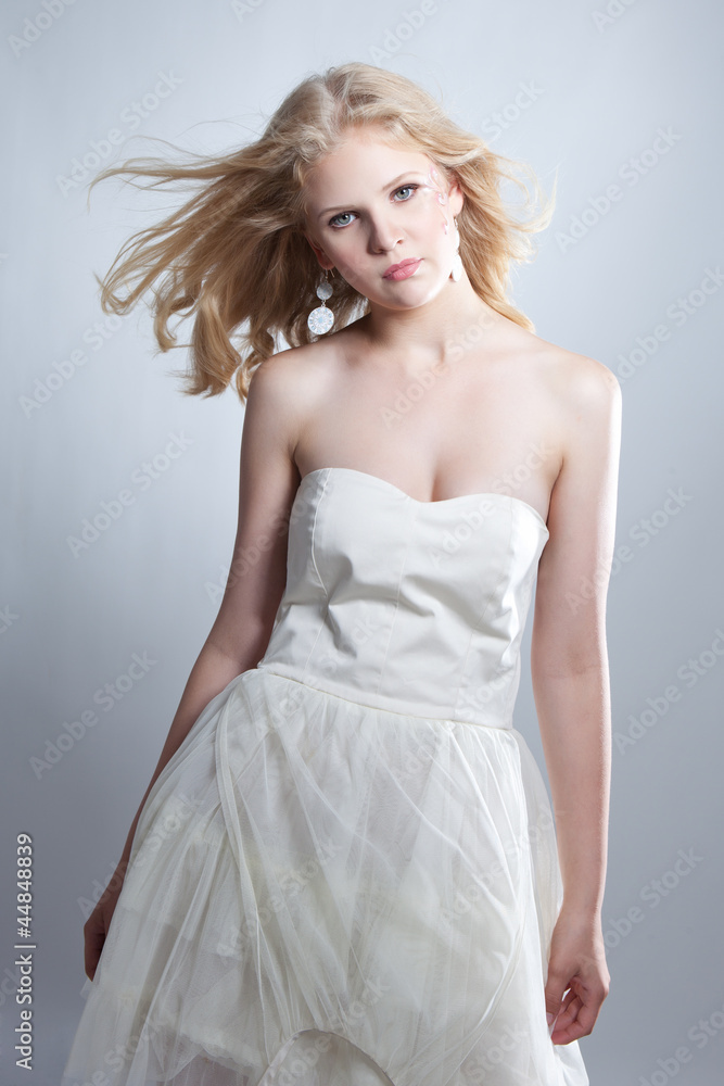 Young blonde girl posing in studio in white dress Young blonde girl posing in studio in white dress