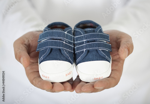 Man holding baby shoes in white photo
