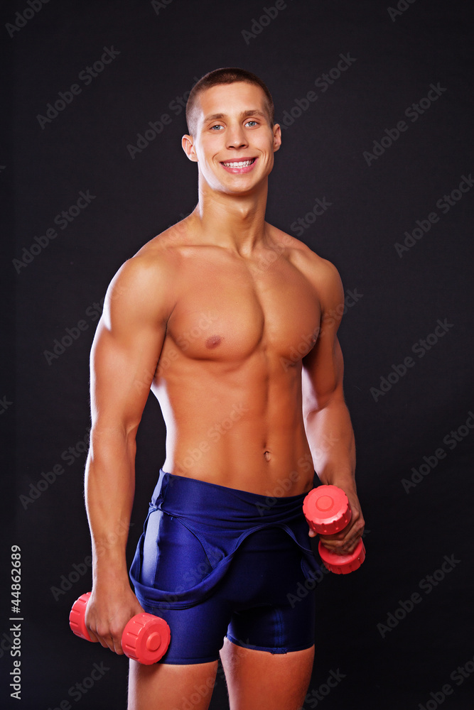 An attractive athlete is playing with dumbbells An attractive athlete is playing with dumbbells