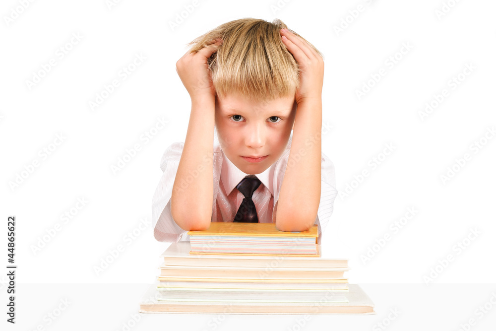 Tired little schoolboy sitting at a table with books isolated on Tired little schoolboy sitting at a table with books isolated on