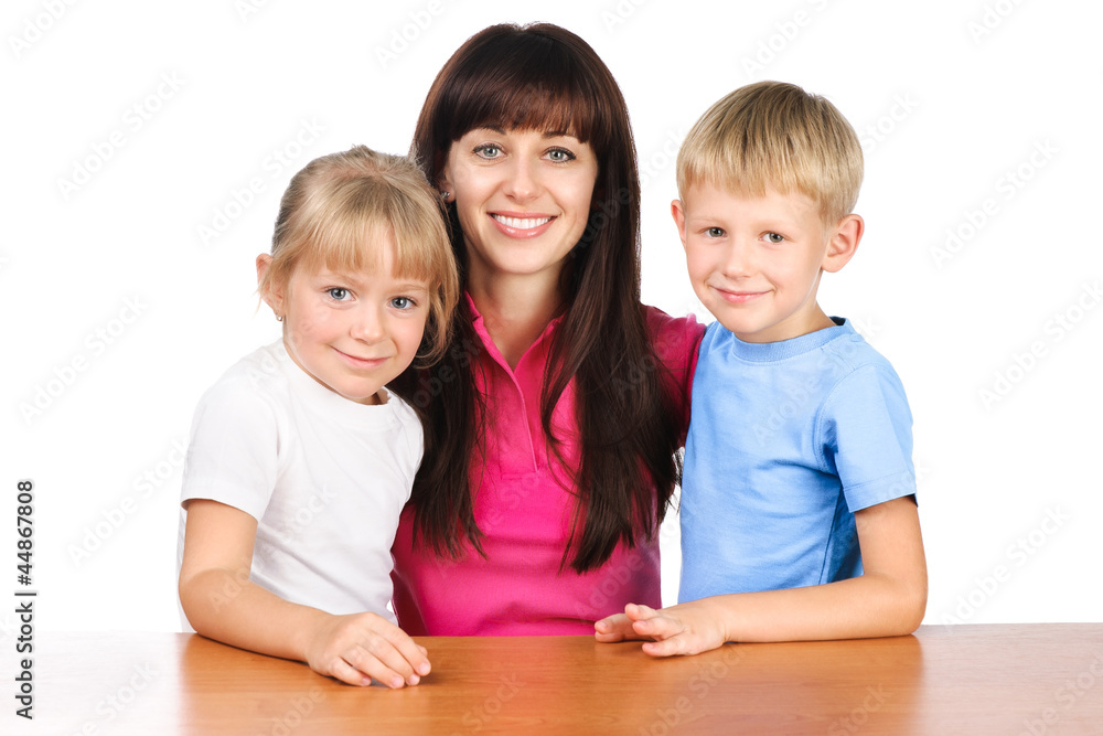 happy mom or young teacher sitting at table with two children is happy mom or young teacher sitting at table with two children is