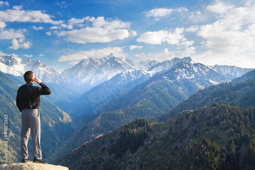 Young businessman talking by phone on the mountain