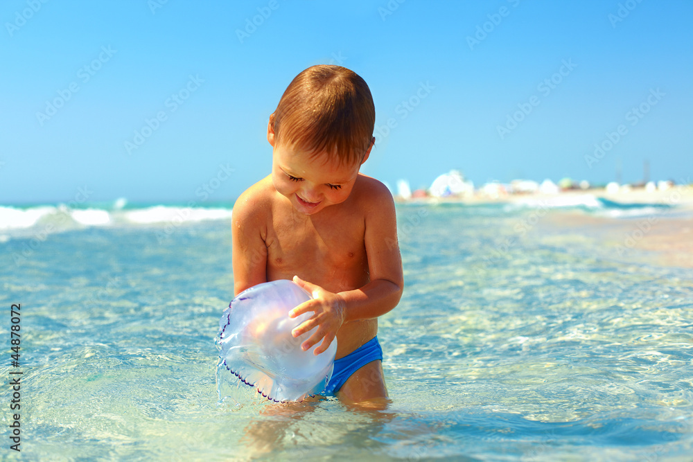 curious baby boy catches jellyfish in the sea curious baby boy catches jellyfish in the sea