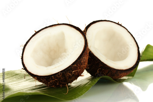 halves of coconut with green leaf on white background close-up