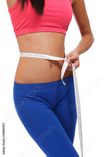 fit young woman measuring her waistline