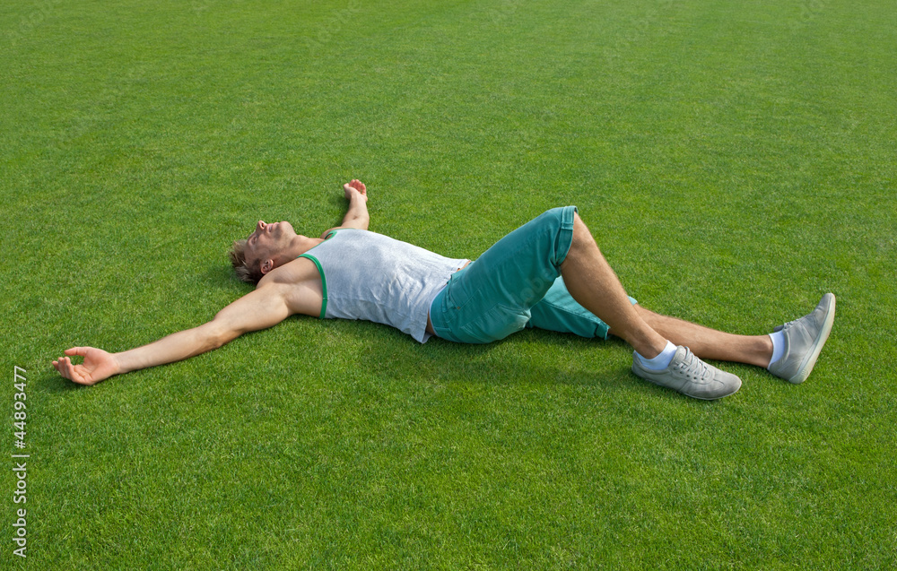 Sporty guy relaxing on green training field Sporty guy relaxing on green training field