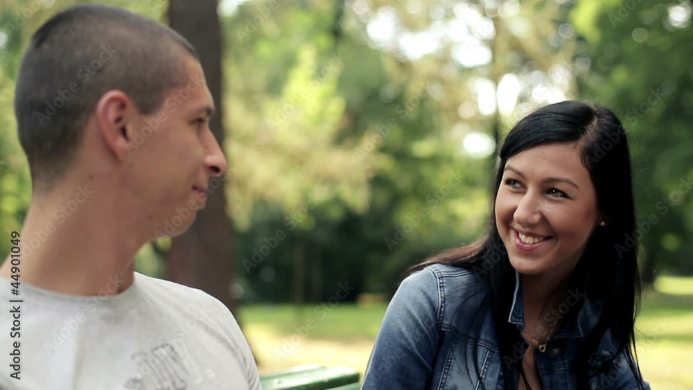 Happy teenage couple chatting in the park, steadicam shot Happy teenage couple chatting in the park, steadicam shot
