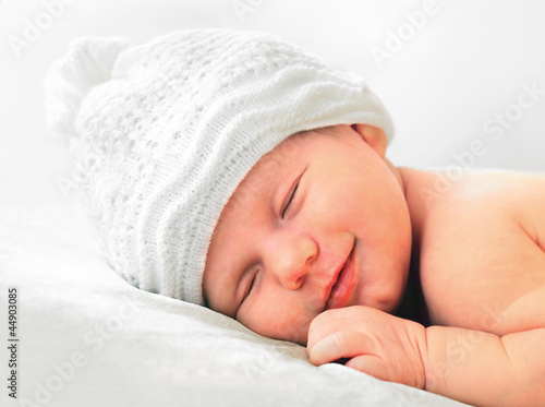 smiling newborn baby in white hat