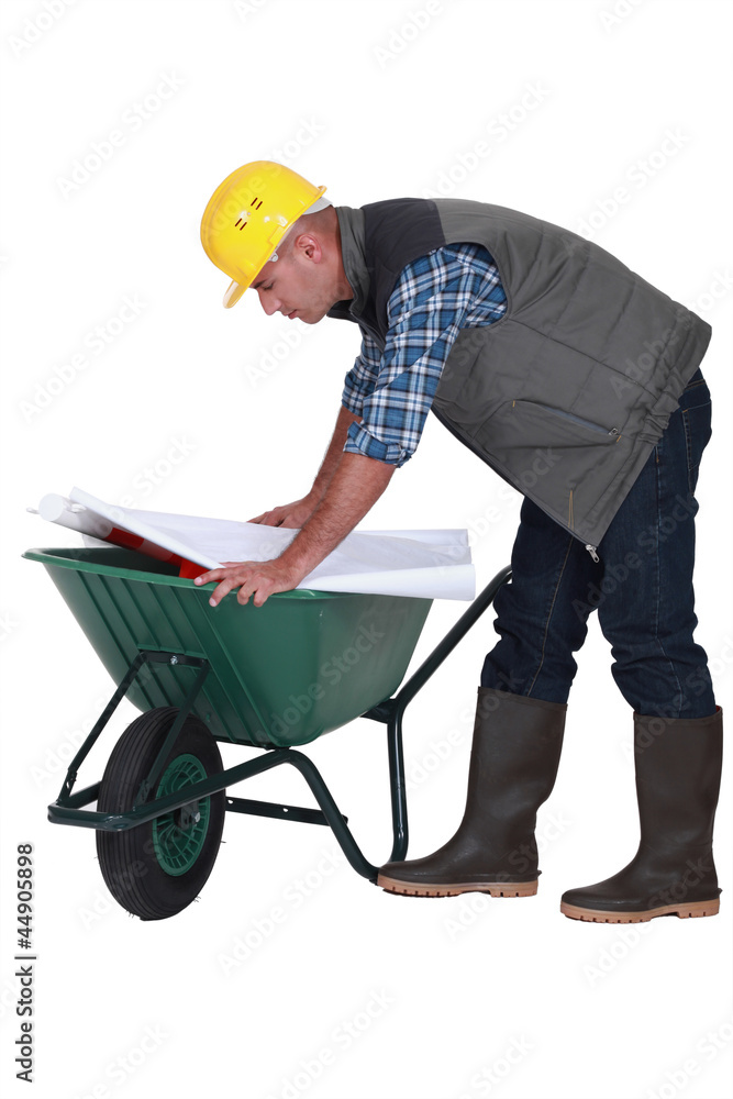 Tradesman looking at a blueprint while leaning Tradesman looking at a blueprint while leaning
