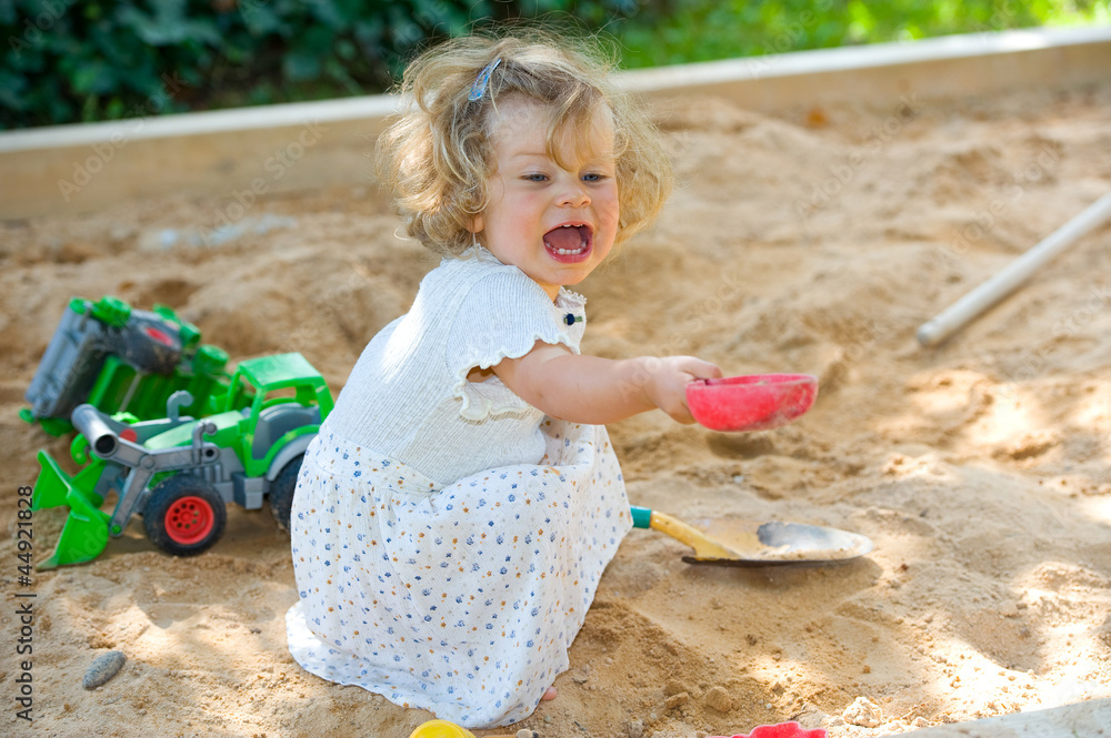 girl is playing in a sandbox - obrazy, fototapety, plakaty 