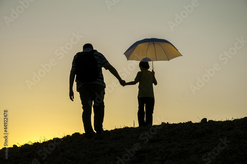 father and son walking in the sunset hand in hand with