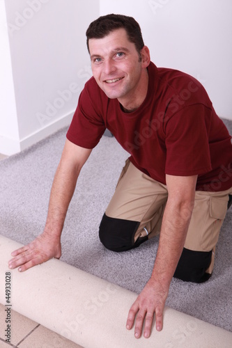 Horizontal image of a man laying carpet