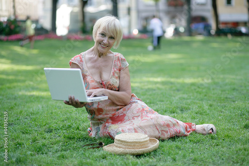 ältere Dame mit Laptop unterwegs photo